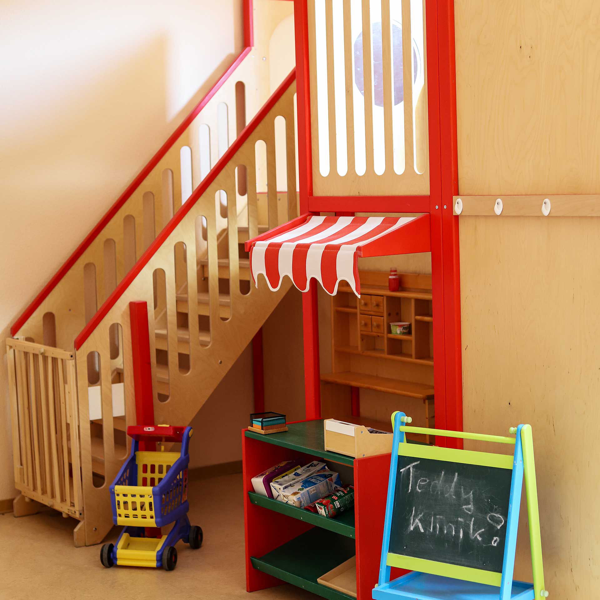 Im Bauzimmer ist eine Treppe und ein Plateau aus Holz. Unter dem Plateau sind unterschiedliche Spielsachen.