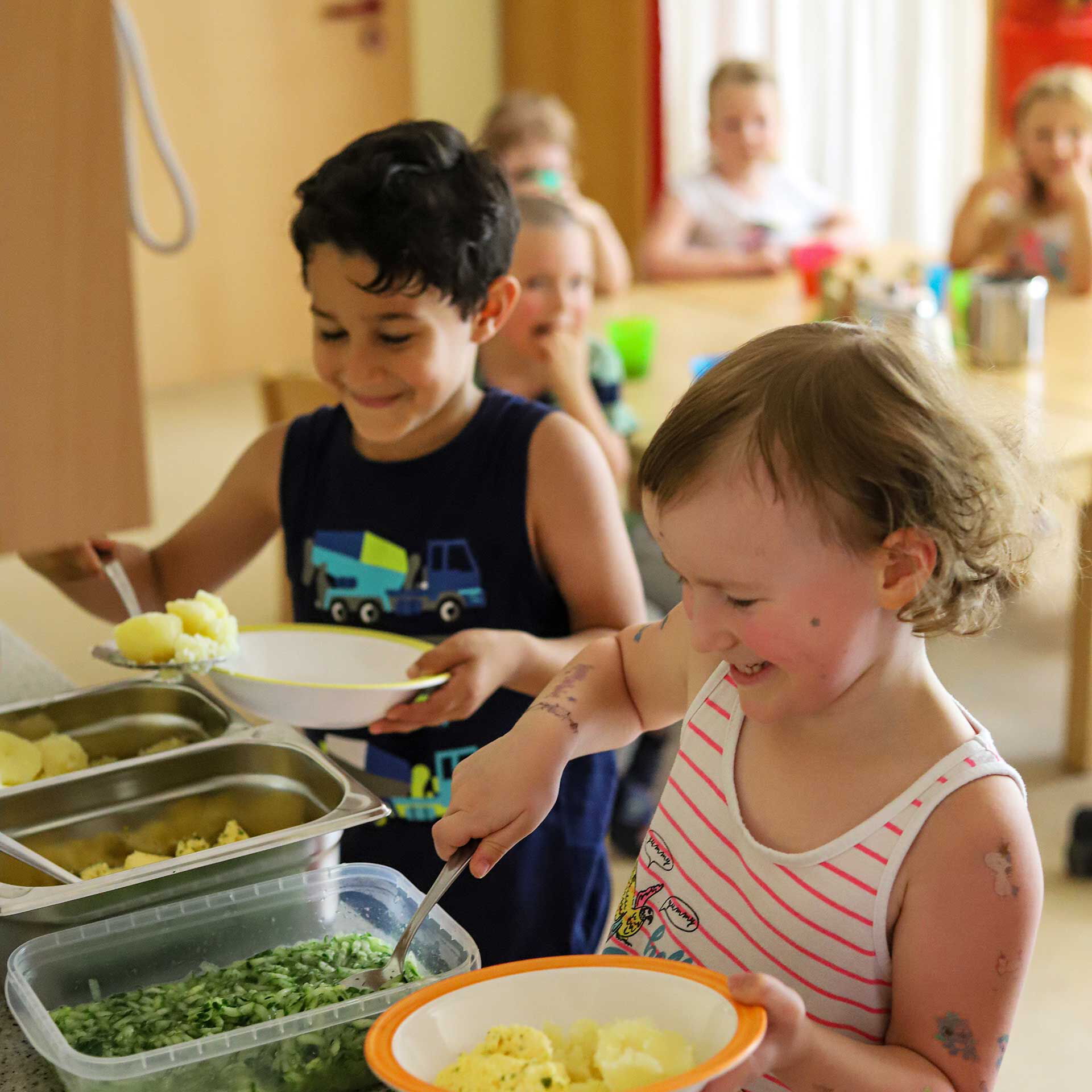 Das Mittagessen wird sich von den Kindern selbst auf den Tellern getan. Es gibt Kartoffeln, Spinat und Ei.