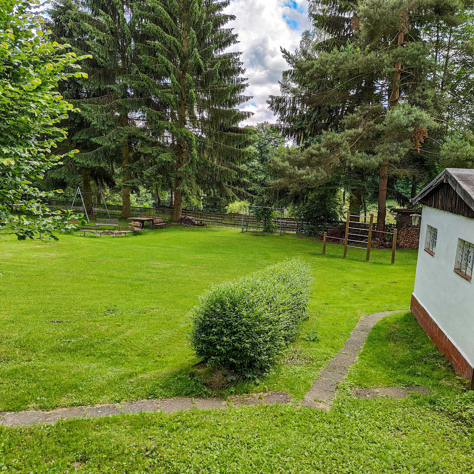 Das großzügige Außengelände mit einem kleinen Fußballplatz im Vordergrund und der Lagerfeuerstelle im Bildhintergrund.