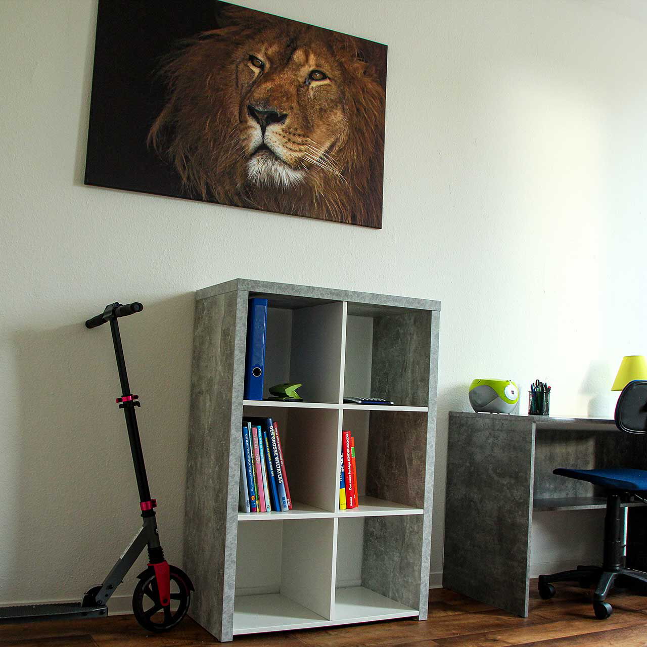 Ein Kinderzimmer mit Schreibtisch, Stuhl, Roller und Bücherregal.