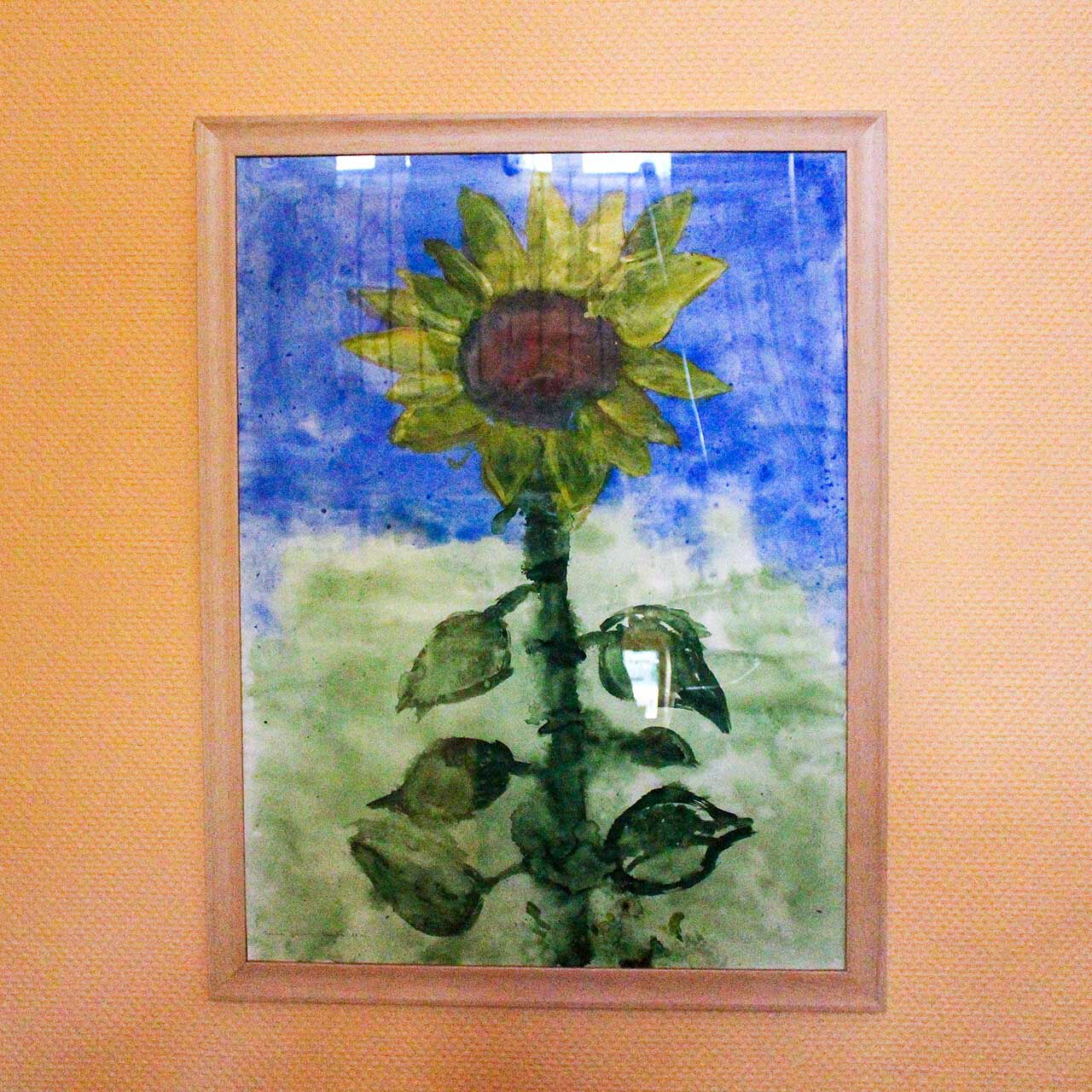 Ein Bild einer Sonnenblume in Form eines Aquarells hängt an der Wand.