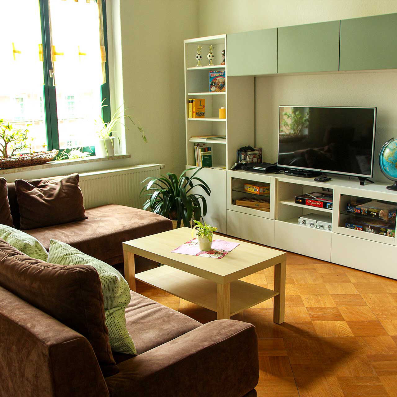 Eine Wohnlandschaft mit einer Anbauwand, TV und einem großen Ecksofa.