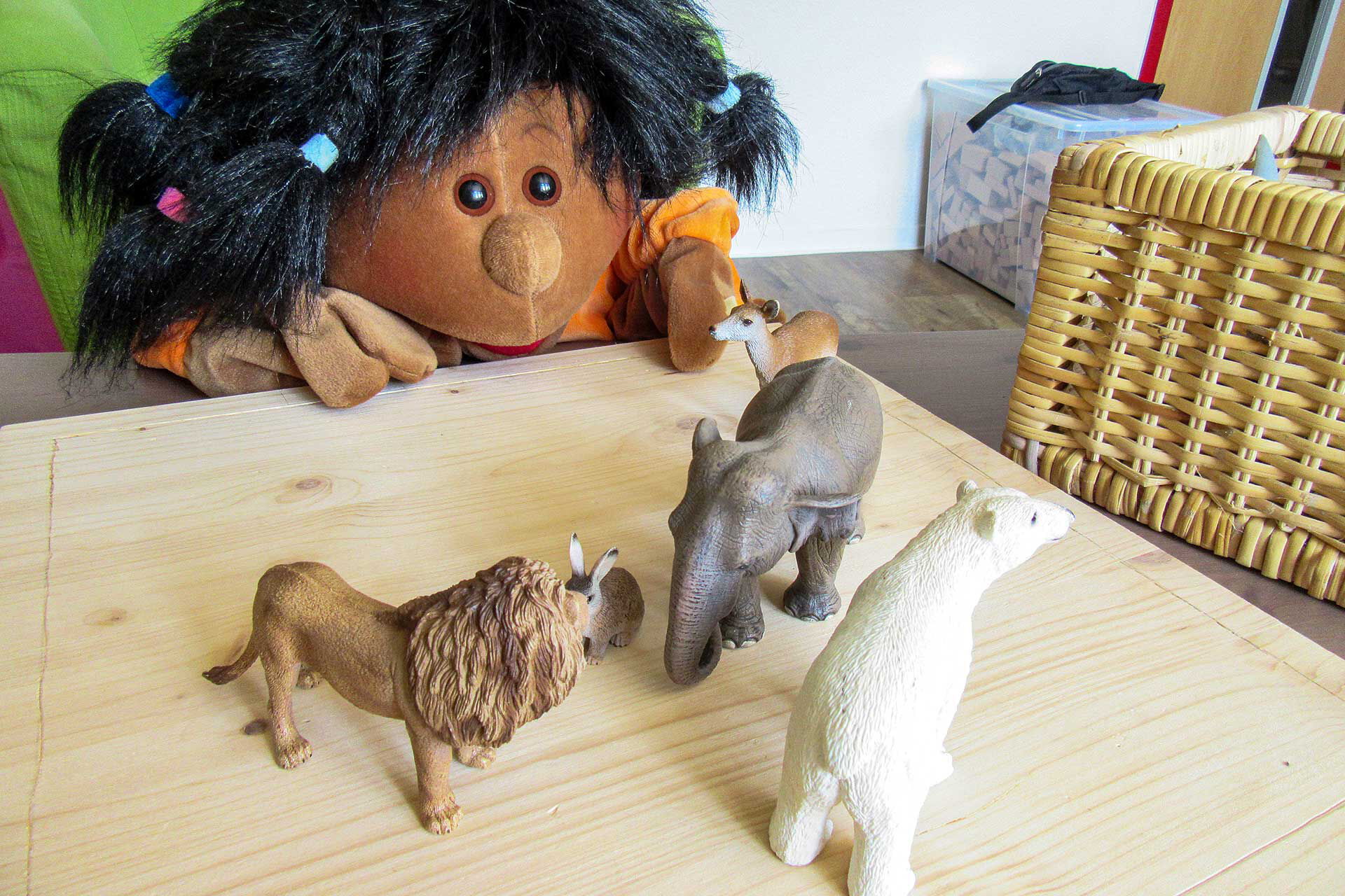 Auf einem Holztisch stehen ein Hase, Reh, Elefant, Löwe und Eisbär.