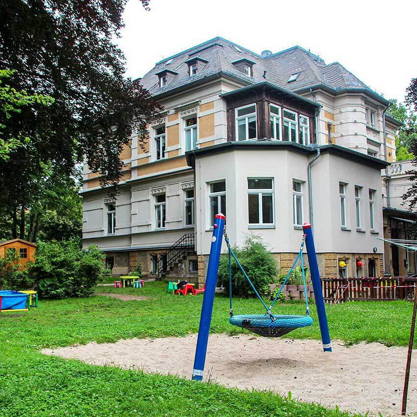 Im Vordergrund ist die Nestschaukel und im Hintergrund steht die Villa.