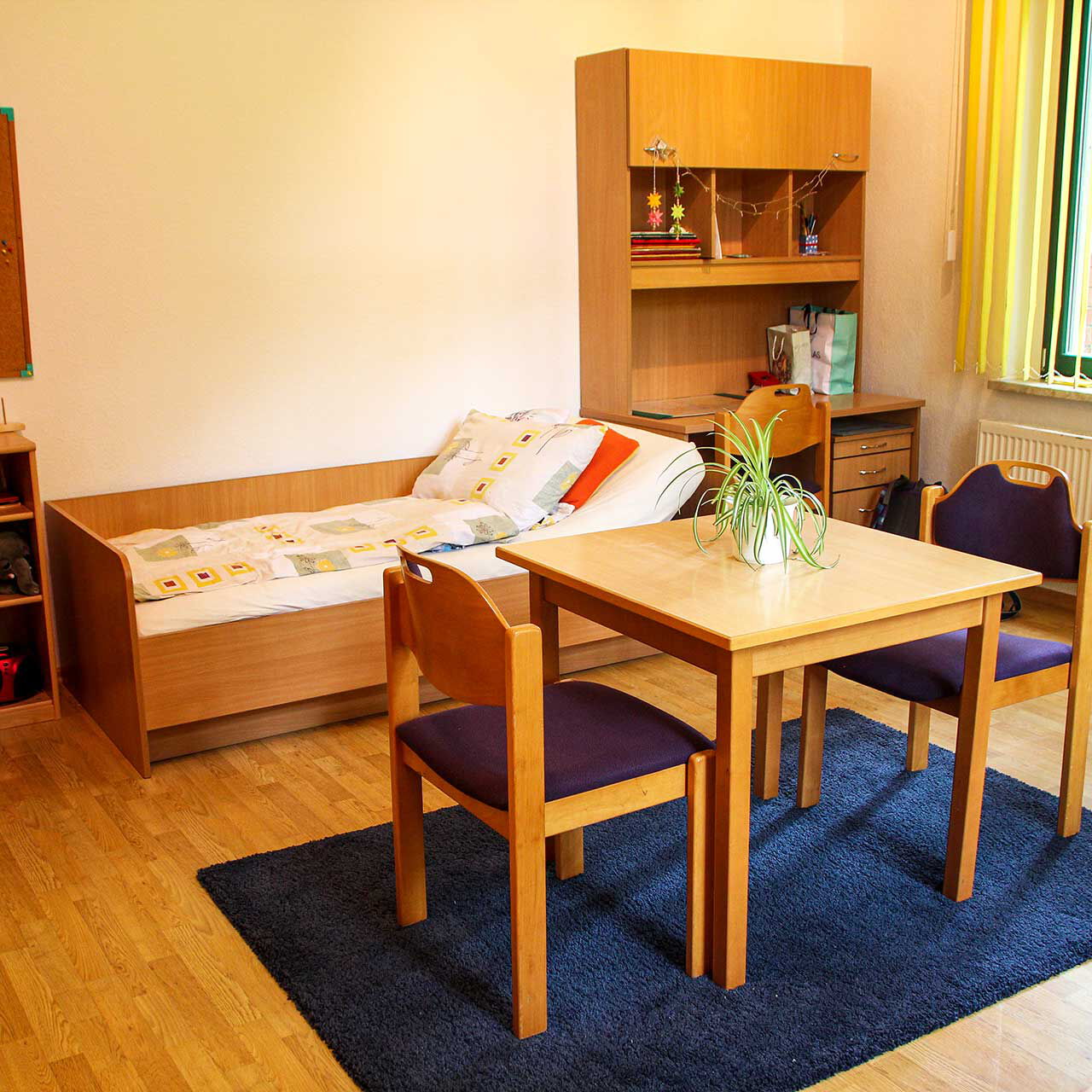 Ein großes Doppelzimmer mit Bett, Schreibtisch und Tischgruppe.