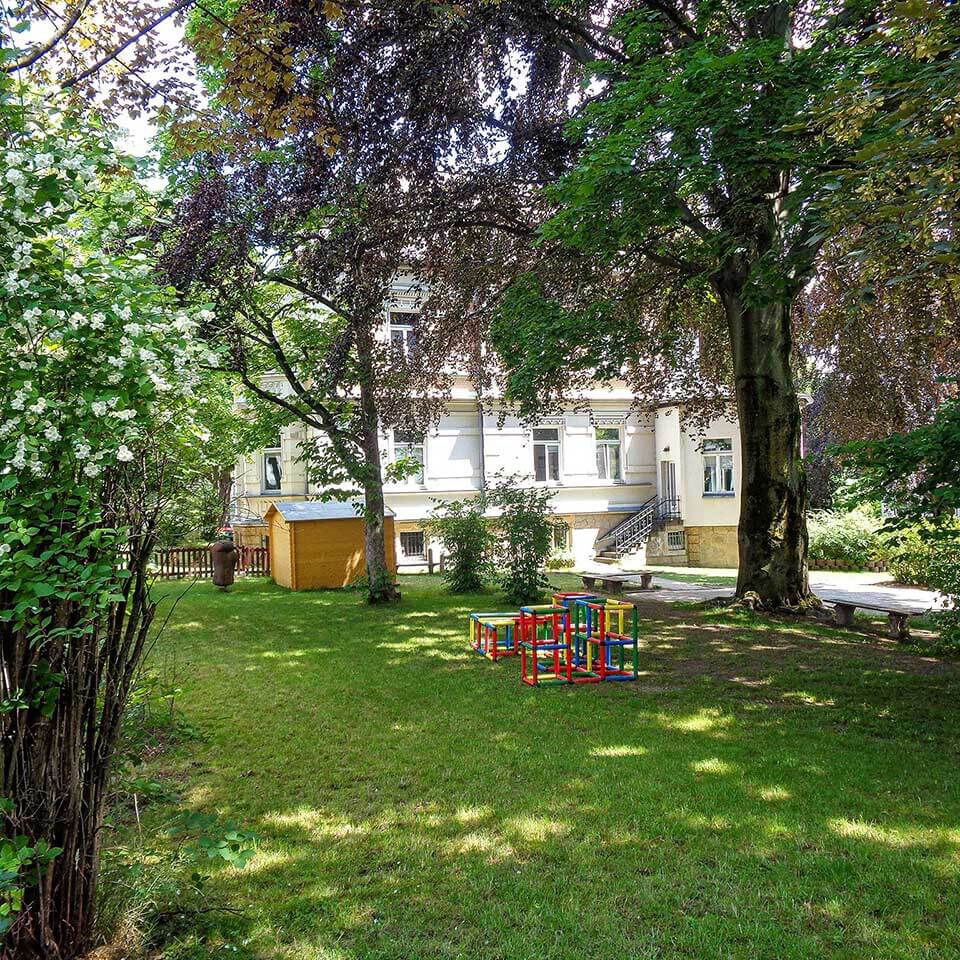 Der große Gartenbereich mit einer Wiese, Bäumen und einer kleinen Holzlaube.