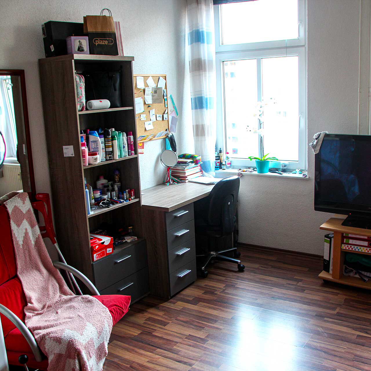 Ein Jugendzimmer mit Schreibtisch, TV und Sessel.
