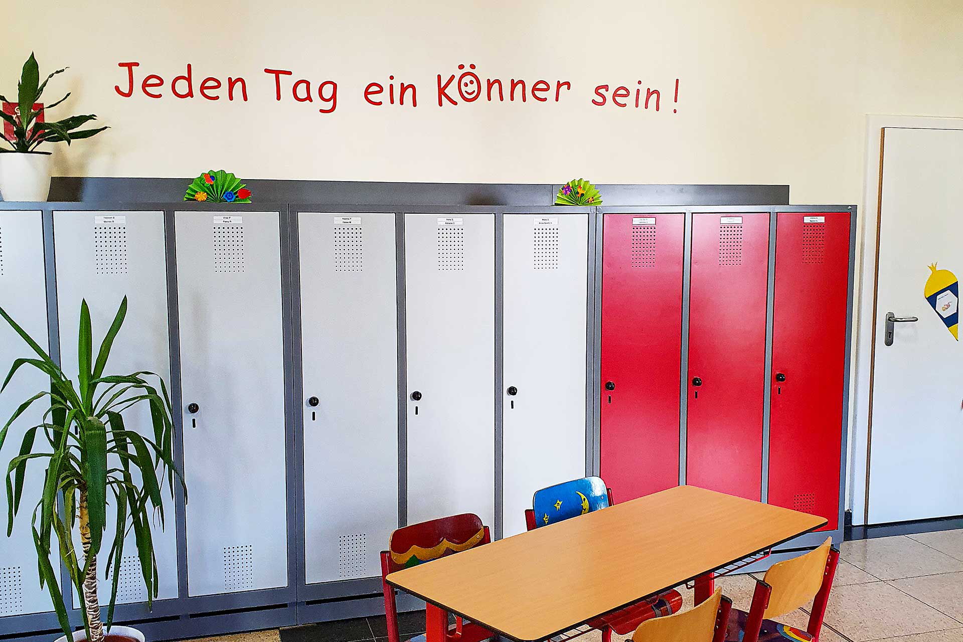 Das Foyer mit einem Tisch und vier Stühlen. Im Hintergrund stehen Schließfächer für die Schüler.