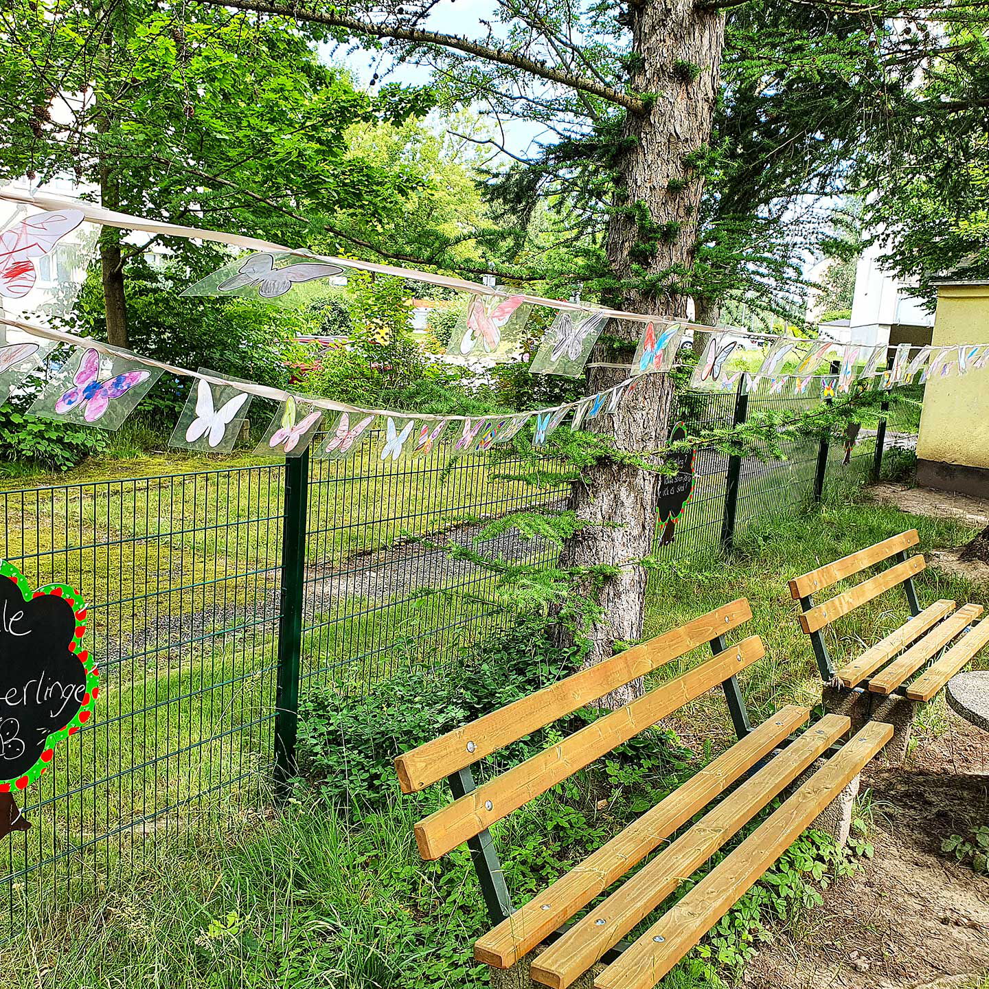 Eine kleine Überraschung zum Kindertag. Es hängen viele bunte selbstgebastelte Schmetterlinge auf der Leine im Außengelände.