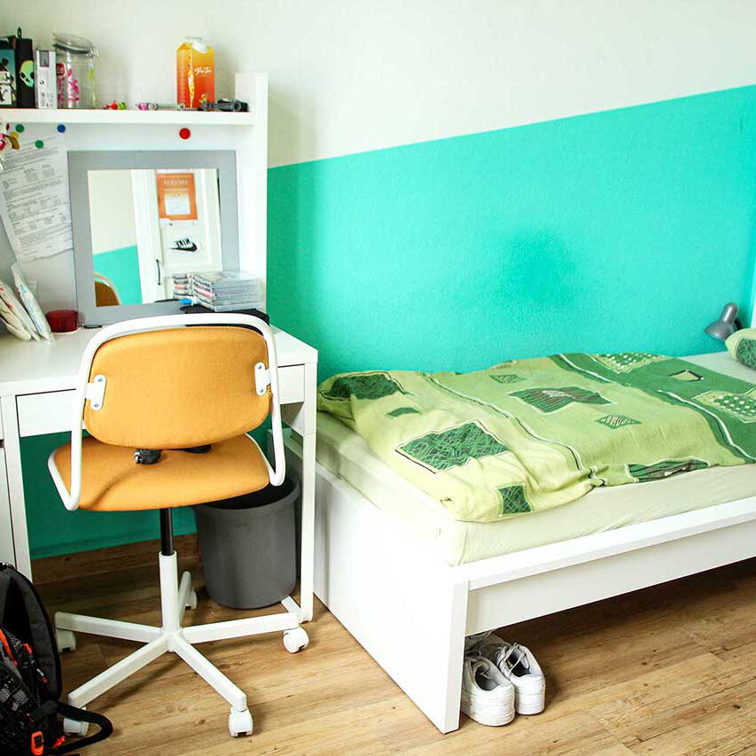 Ein Jugendzimmer mit einem Schreibtisch und Bett.