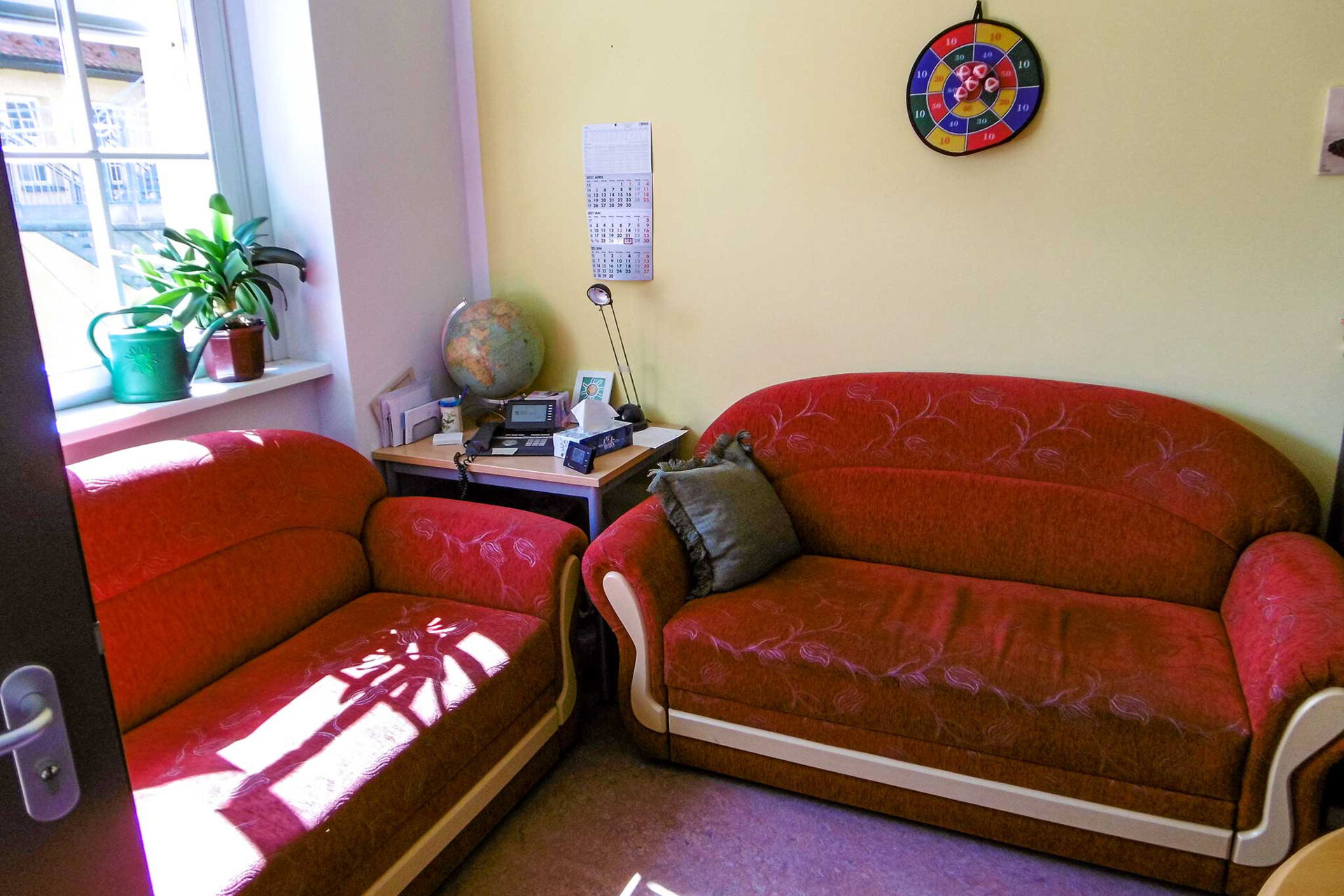 Der Sitzbereich in den Räumen der Inklusionsassistenz. Es stehen zwei rote Sofas im Raum.