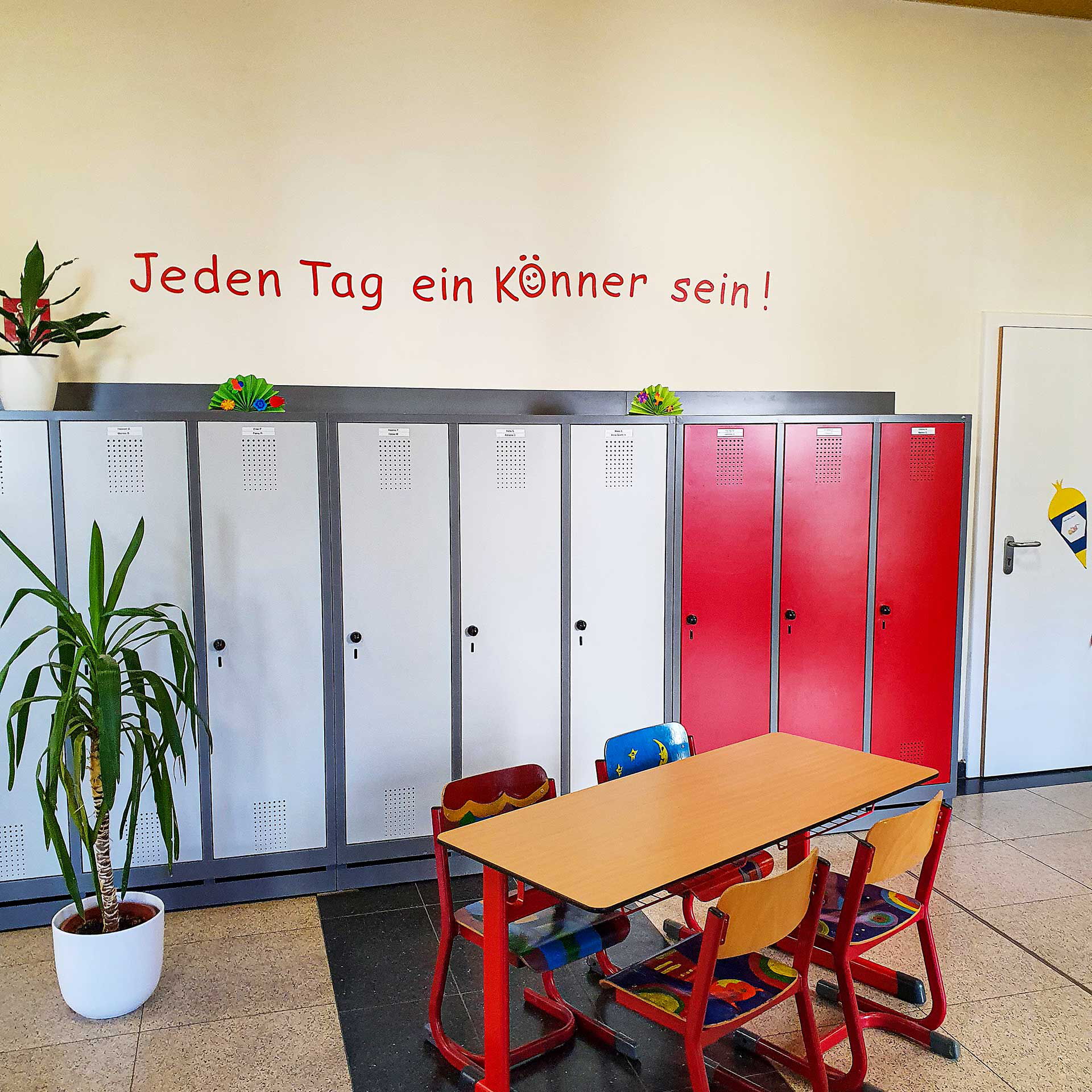 Das Foyer mit einem Tisch und vier Stühlen. Im Hintergrund stehen Schließfächer für die Schüler.