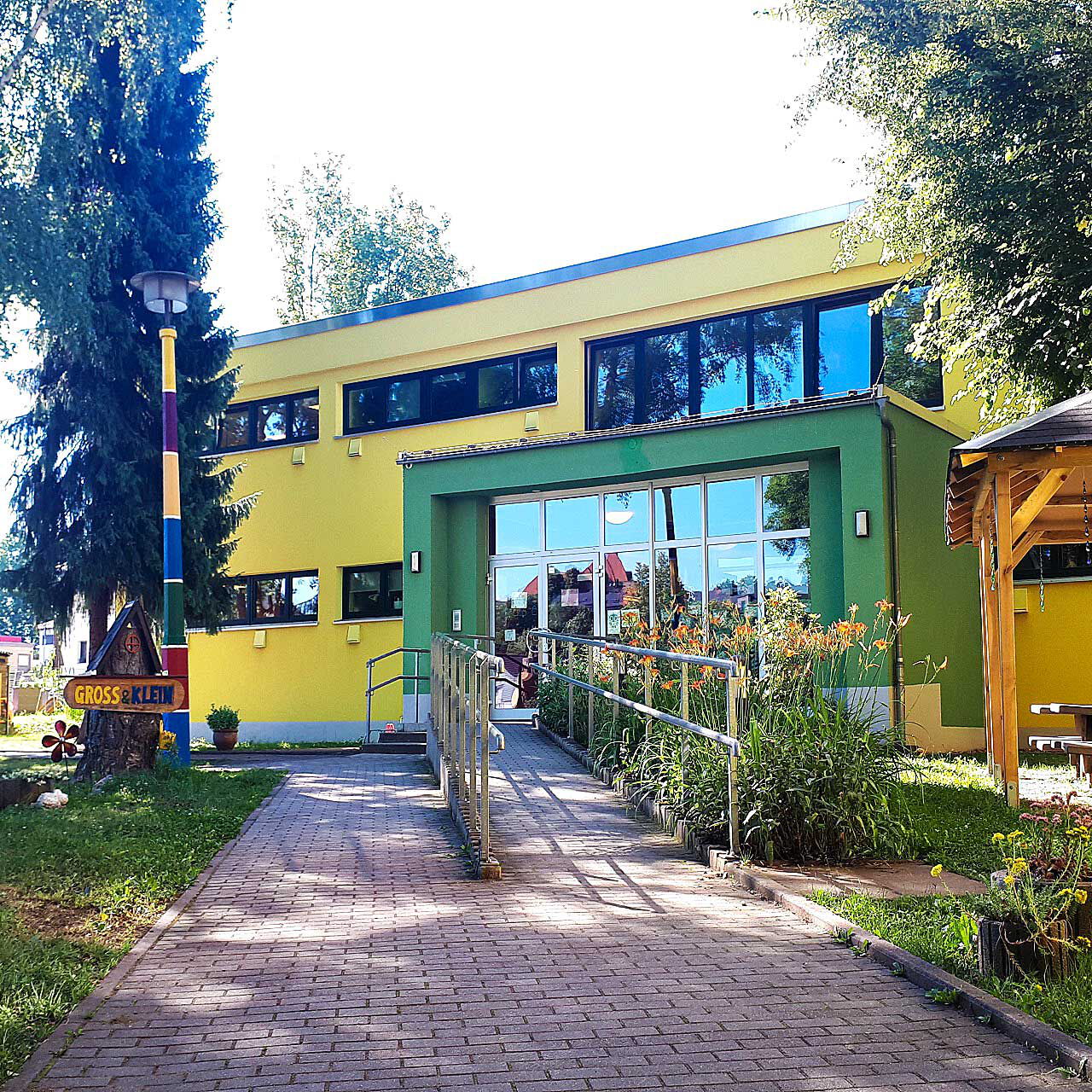 Der Eingangsbereich der Kita Spielhaus Groß & Klein mit einer Rampe und Treppenaufgang.