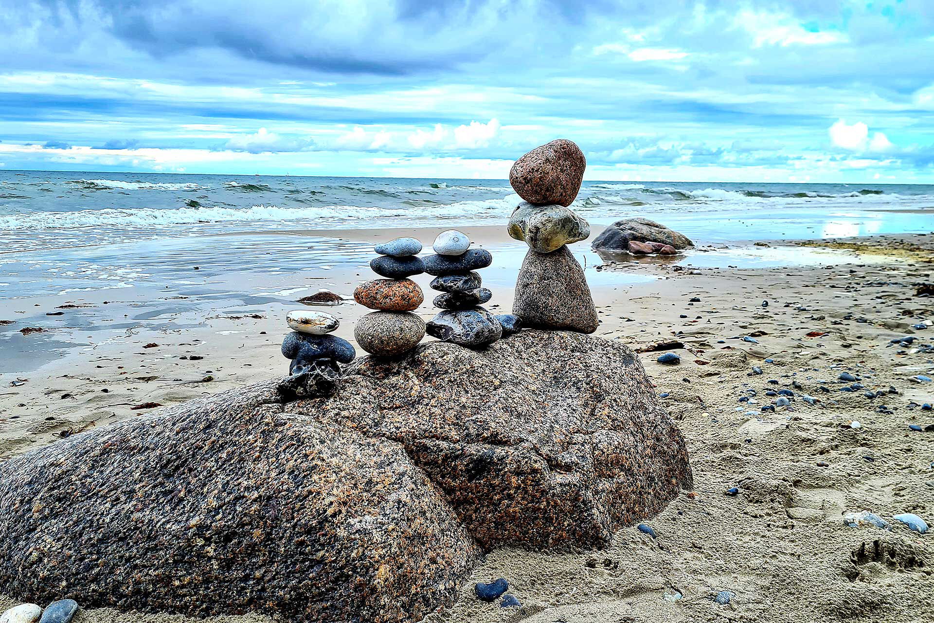 4 Steintürme stehen auf einem Felsen am Strand.