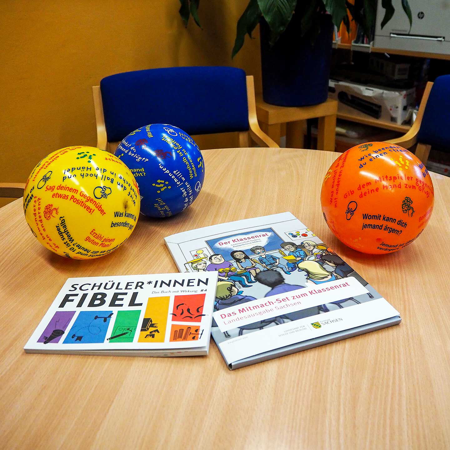 Im Büro der Schulsozialarbeit steht ein Tisch im Vordergrund und darauf liegen drei Bälle und zwei Zeitschriften.