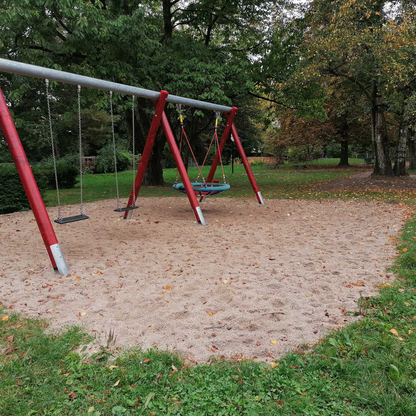 Eine Nestschaukel im Bildhintergrund und zwei einzelne Schaukeln im Vordergrund.