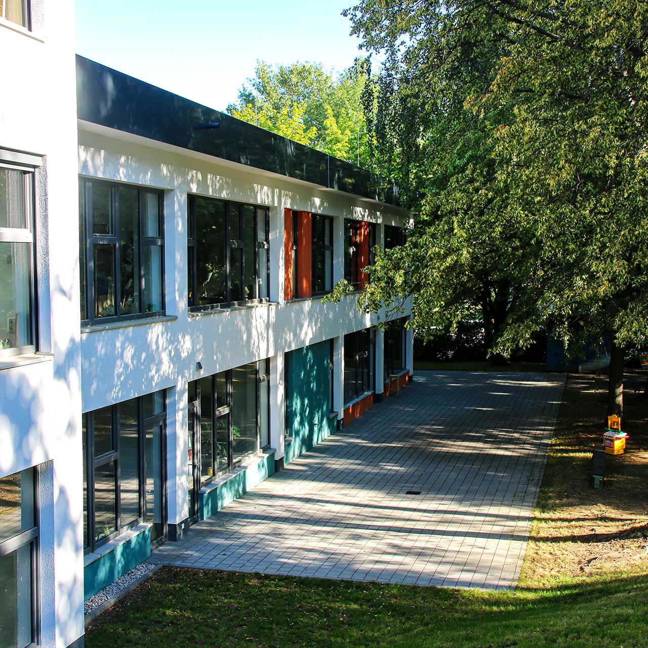 Das Außengelände des Jugendklubs EL ZWO im Haus Liddy mit einem großen Terrassenbereich, vielen Bäumen und einer großen Wiese.