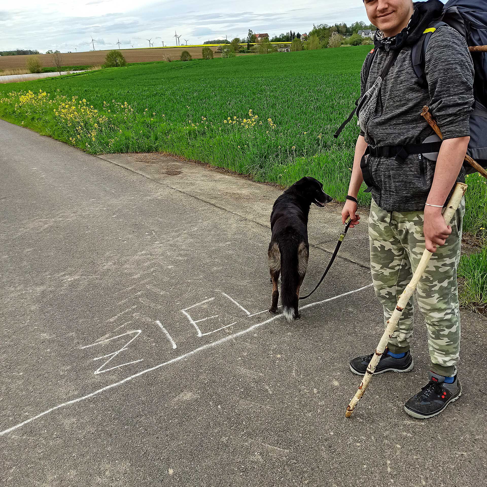 Ein Jugendlicher steht vor seinem Zielpunkt auf dem Wanderweg.