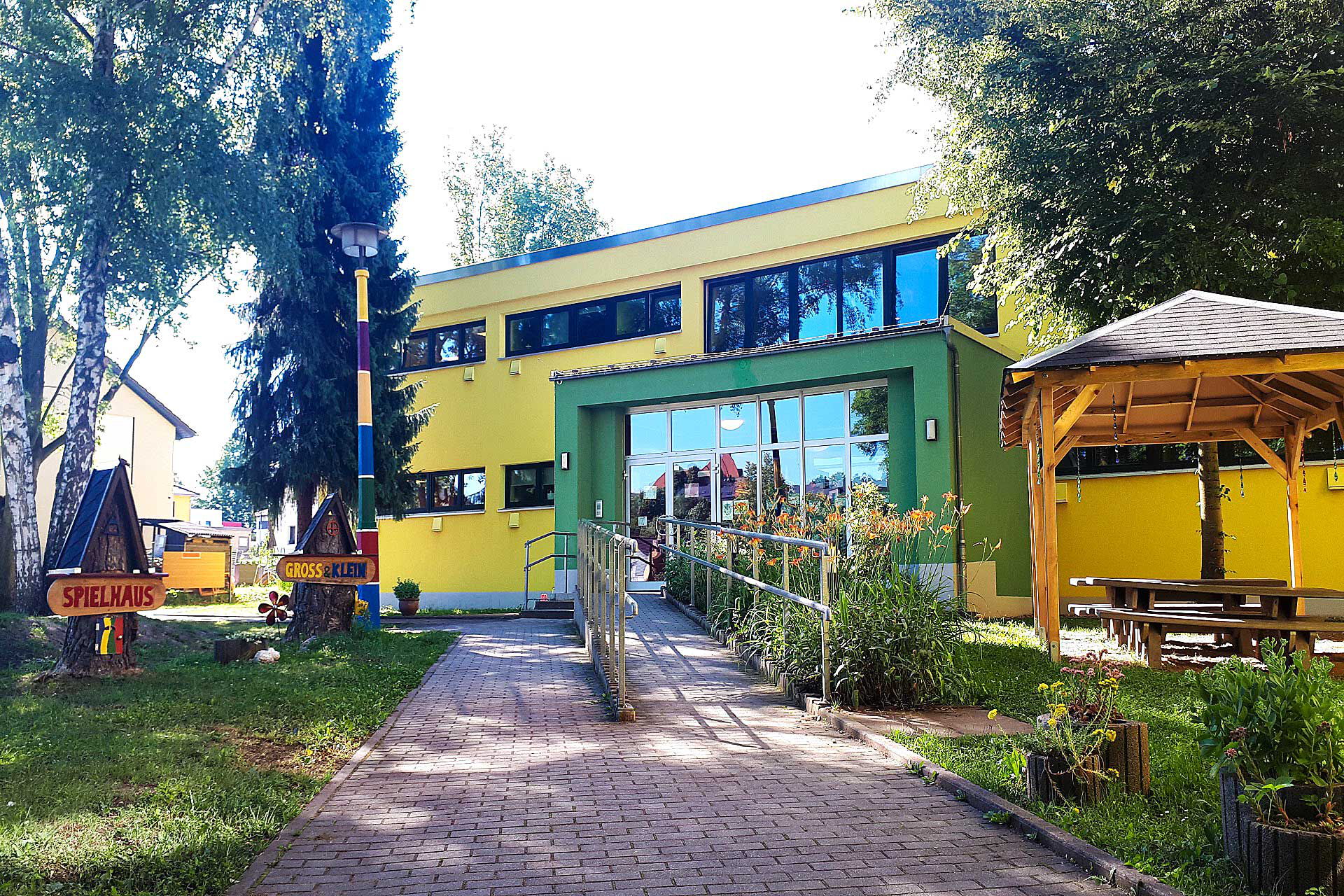 Der Eingangsbereich der Kita Spielhaus Groß & Klein mit einer Rampe und Treppenaufgang.