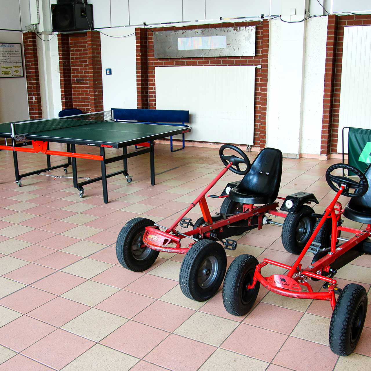 Die Kettcars stehen in der Spielhalle neben der Tischtennisplatte.