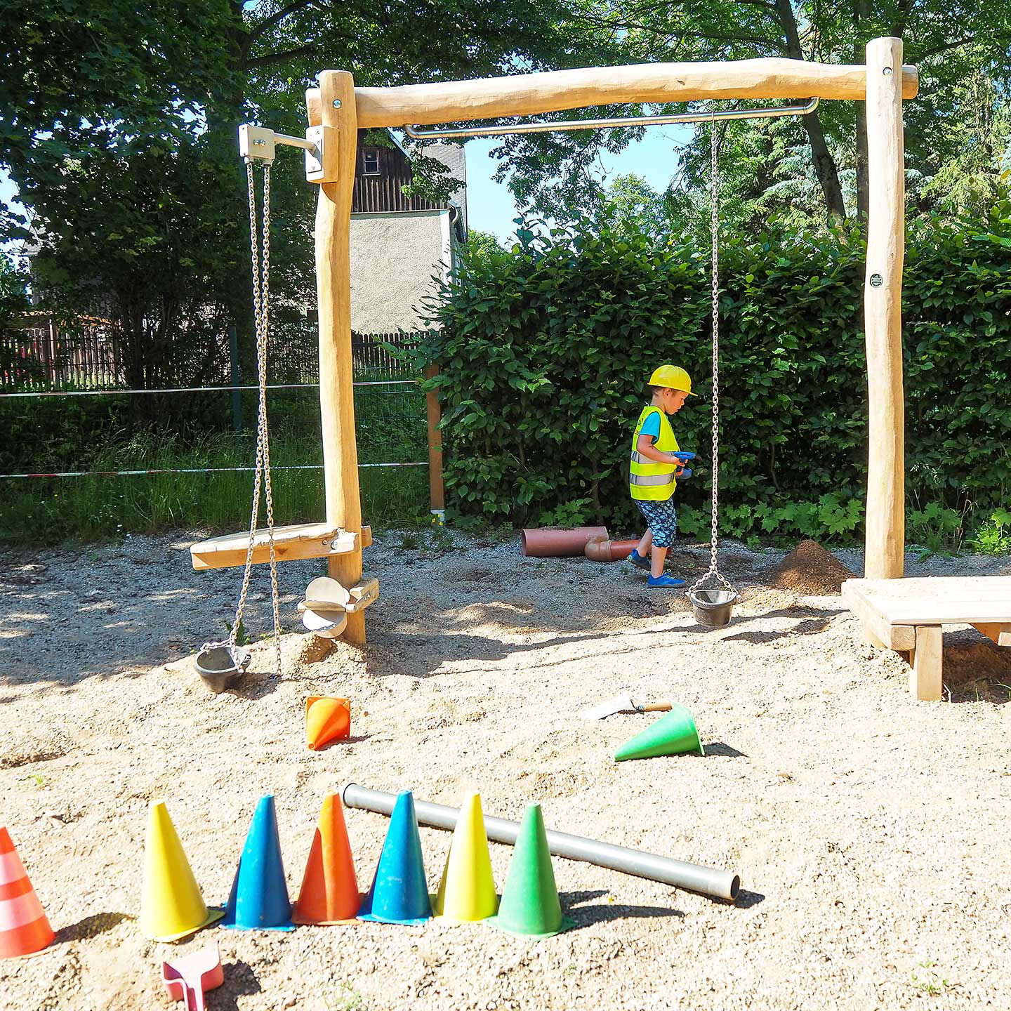 Ein Sandkasten im Außengelände mit mehreren Bereichen zum spielen und graben.