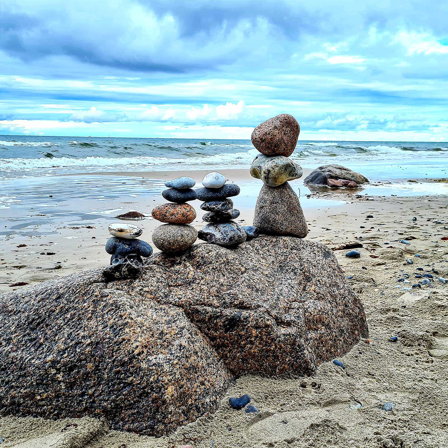 4 Steintürme stehen auf einem Felsen am Strand.