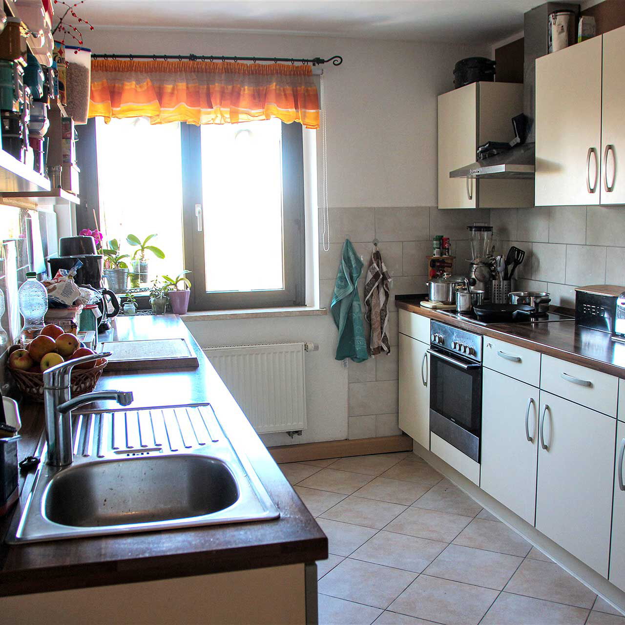 Eine Küche mit einer Küchenzeile auf der rechten Seite und den Spül- und Arbeitsbereich auf der linken Wandseite.
