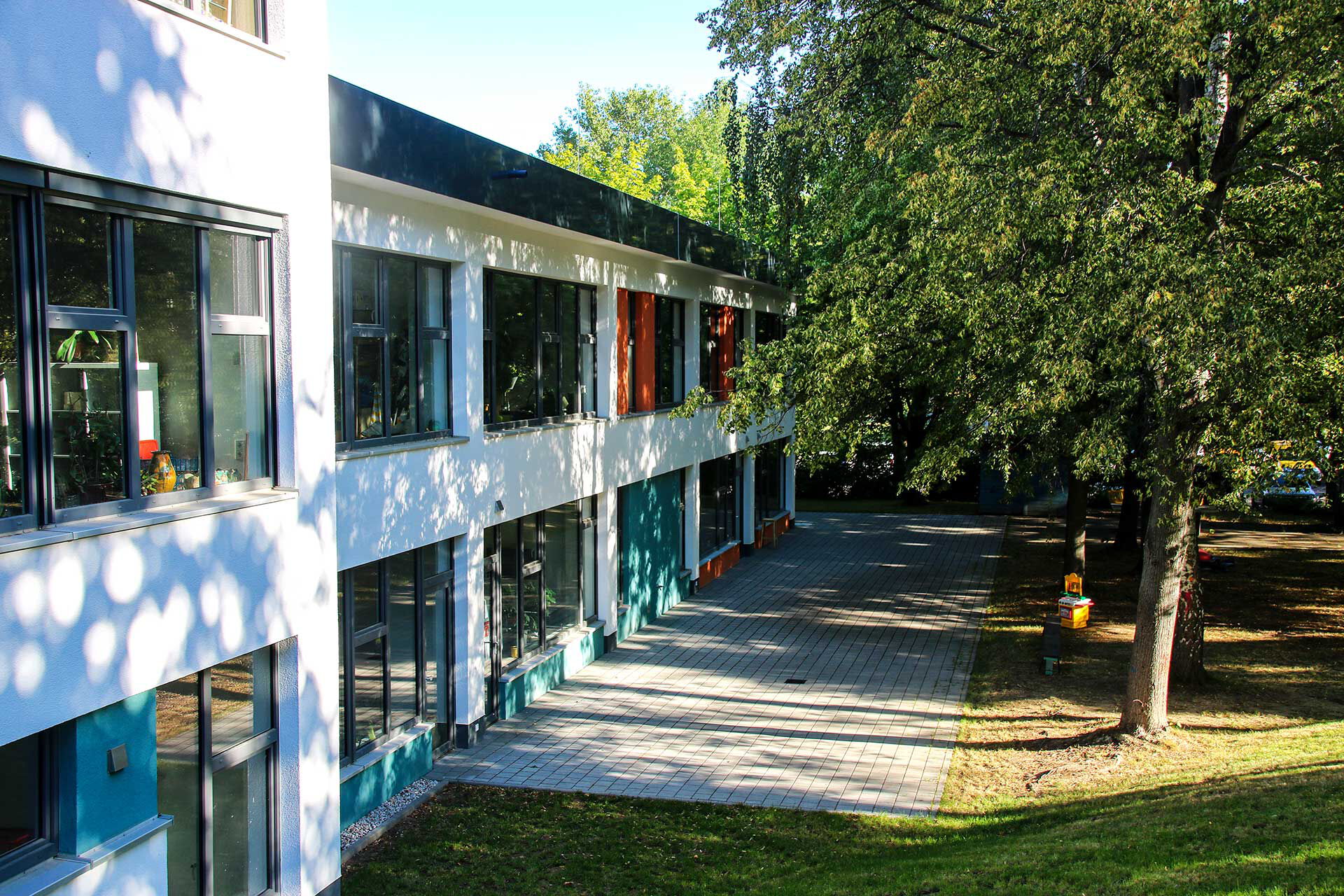 Das Außengelände des Jugendklubs EL ZWO im Haus Liddy mit einem großen Terrassenbereich, vielen Bäumen und einer großen Wiese.